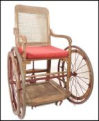 An early 20th century World War One cane back wheelchair - invalids chair. Original painted cast