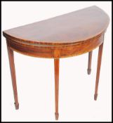 A 19th century Georgian mahogany inlaid demi-lune games card table being raised on square tapering