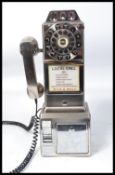 An American style contemporary coin operated wall telephone by Wild and Wolf having a ring dial