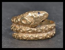 A hallmarked vintage 9ct gold ring in the form of a coiled snake having sapphire eyes. Hallmarked