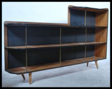 A retro 1950's mid century teak wood bookcase having multiple shelves with ebonised and brass rod