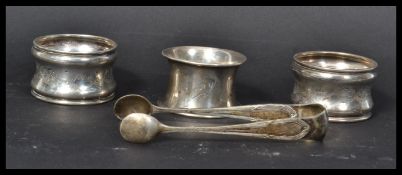 A group of silver hallmarked items to include a pair of sugar tongs and three silver napkin rings.