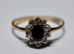 A hallmarked 9ct gold blue and white stone ring. The central blue stone having a halo of smaller