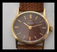 A 14ct gold cased Omega watch of oval form having a Moroccan leather / snakeskin effect dial with