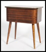 A vintage retro 20th century teak sewing box raised on tapering legs with hinged lid opening to
