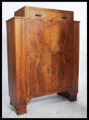 A 1930's Art Deco walnut cocktail cabinet having a fall front drinks cabinet set over a cupboard