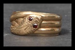 A hallmarked 9ct gold and red stone band ring in the form of a snake with red gem set eyes.