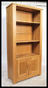 A contemporary chunky oak upright bookcase cabinet with cupboard to the base having shelves above.