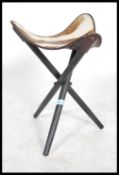 A 1970's Safari stool being raised on an ebonised folding tripod vase having a good animal hide /