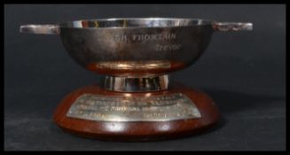 A hallmarked silver quaich having Celtic motif handles. Raised on a wooden base with hallmarked