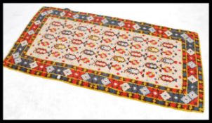 A 20th century woollen floor rug with central  panel on beige ground within geometric borders.