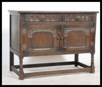 An Ercol style Old Colonnial oak dresser base being raised on turned legs with carved door cupboard.