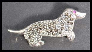 A sterling silver and marcasite brooch of a dachshund dog with inset ruby eye.