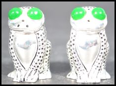 A pair of continental silver condiments in the form of toads having large green stone eyes. Weighs