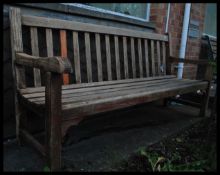 A 20th century teak wood garden bench having slatted seat and back rest flanked by shaped elbow