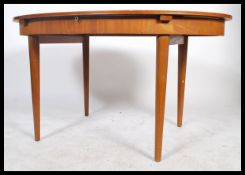 A retro 1960's teak wood extending dining table of oval  form raised on tapering legs having a