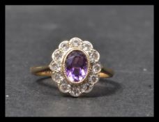 A hallmarked 9ct gold ring stet with a central oval mixed cut purple stone surrounded by a halo of