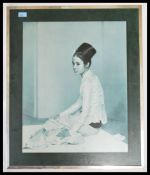 A mid century retro mounted print of a Malaysian girl in robes being signed by the artist with