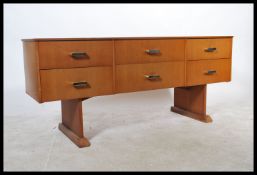 A retro 1970's teak wood sideboard being raised on angular legs with a series of drawers to the wide