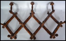 An early 20th century faux bamboo ten peg hat and coat rack having a metamorphic scissor arm action.