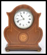 An Edwardian mahogany inlaid mantel clock being raised on brass bun feet, cylinder movement with