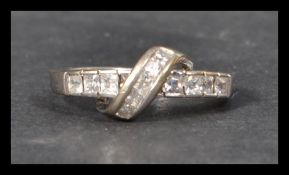 A hallmarked 9ct white gold and CZ ring  having princess cut stones in a channel crossover band