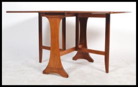 A 1970's teak wood Danish influenced G-Plan drop leaf dining table raised on shaped supports with
