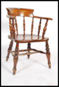 A 19th century elm and beechwood smokers bow elbow chair with turned spindle back, saddle shaped
