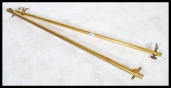 A pair of Victorian style brass curtain rails. Each with cylindrical tubes set to shaped wall