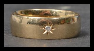A hallmarked 9ct gold and diamond band ring having a single star set diamond. Hallmarked London.