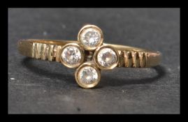A hallmarked 9ct gold and white stone ring having quatrefoil bezel set sones with stylised