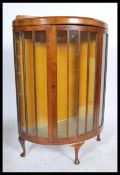 A 1930's Queen Anne walnut china display cabinet being raised on cabriole legs with glass shelves.