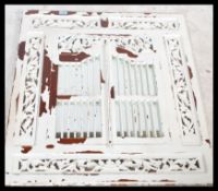 A vintage style wall mirror having fret carved hinged shutters fitted and finished with a shabby