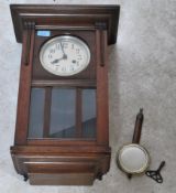 A 1920's oak wall clock having silvered dial with faceted hands over pendulum window. The case