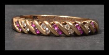 A hallmarked 9ct gold ruby and diamond band ring having round cut rubies and diamonds in a raised
