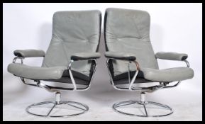 A pair of retro 20th Century Swedish swivel reclining armchairs in the manner of Ekornes, raised