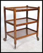 A vintage early 20th century / 1930's oak 3 tier trolley being raised on the original castors having