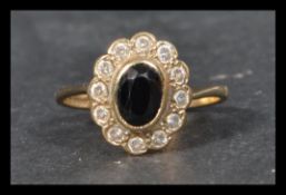 A hallmarkeed 9ct gold ring set with a central oval cut sapphire surrounded by a halo of white