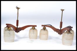 A pair of vintage retro 20th century teak wood three branch ceiling lights having frosted glass