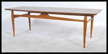 A 1970's retro Danish inspired teak wood large coffee table being raised on turned legs with