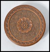 A 19th century wooden needle box of circular form having a central flower heat with stitch