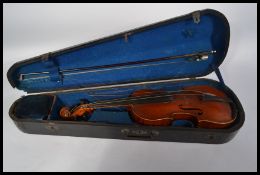 A 19th / 20th century cased violin with a two-part back, scrolled end and boxwood pegs , mother of