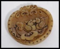 A carved jade Chinese jade bi disk with scrolled decoration and birds.