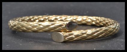 A hallmarked 9ct gold crossover bangle bracelet having a diamond cut design. Hidden split open clasp