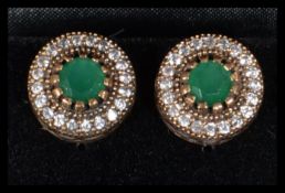A pair of sterling silver and CZ earrings of roundel form having central green stones. Complete in