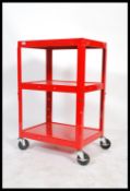 A vintage style industrial two tier trolley raised on large castors having a vibrant red enamel