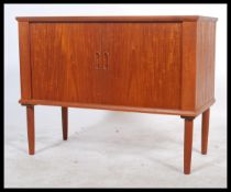 A 1970's retro Danish inspired teak wood tambour fronted record cabinet. The twin roll front doors