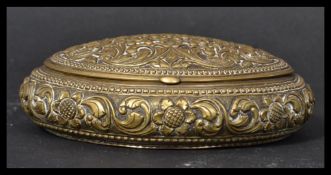 A 19th century brass snuff pot having a scrolled design with flower heads and beaded borders.
