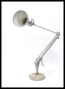 A vintage 20th century retro industrial anglepoise desk lamp raised on a circular base with