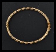 A hallmarked 9ct gold bangle bracelet having alternating half engraved bands. Weighs 4.4 grams.